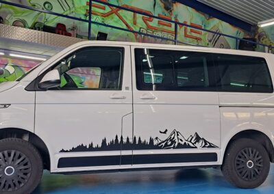 Weisser VW Bus mit schwarzer Berglandschaft-Folierung
