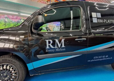 Schwarzer Transporter mit blau-weisser Firmenbeschriftung