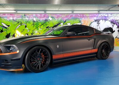 Ford Mustang mit mattschwarzer Folierung und orangefarbenen Akzenten