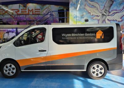 Weisser Transporter mit orange-grauer Firmenbeschriftung