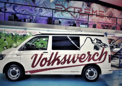 Weisser VW Bus mit grosser Volkswerch Fahrzeugbeschriftung